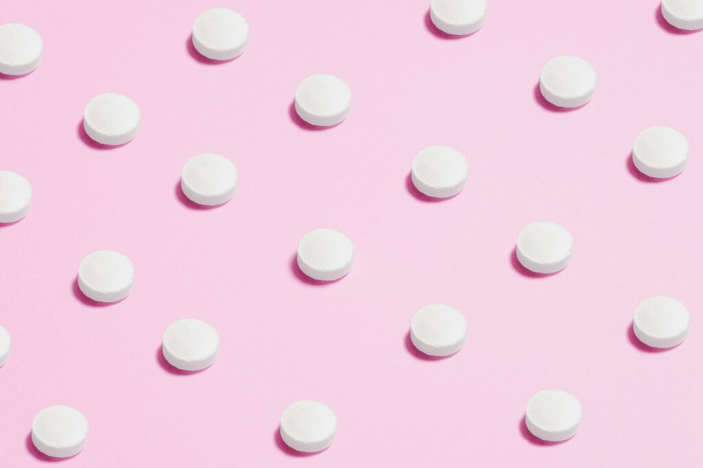 white round pills against pink background